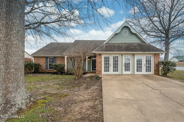 view of front of home with a shingled roof, french doors, and brick siding