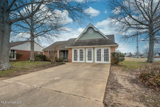 view of front of home featuring brick siding, a shingled roof, and french doors