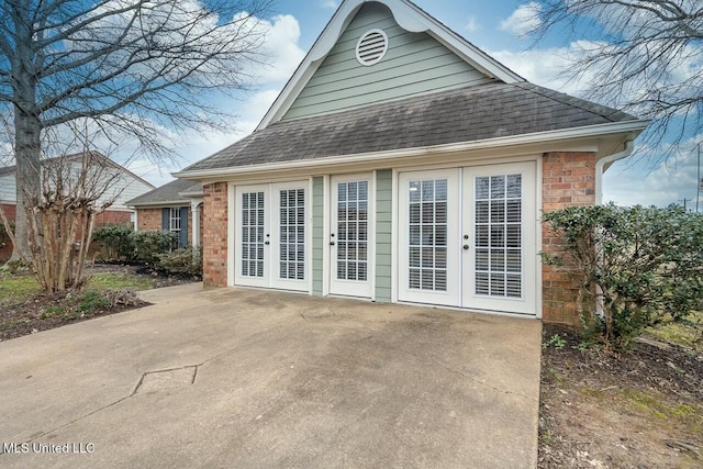 rear view of house featuring a shingled roof, french doors, and brick siding