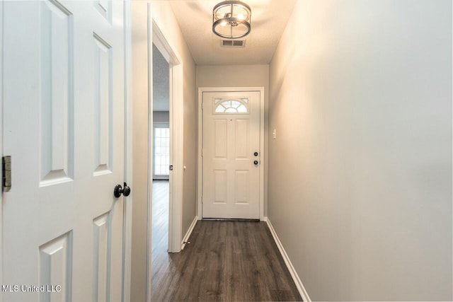 doorway featuring baseboards, visible vents, dark wood finished floors, and a textured ceiling