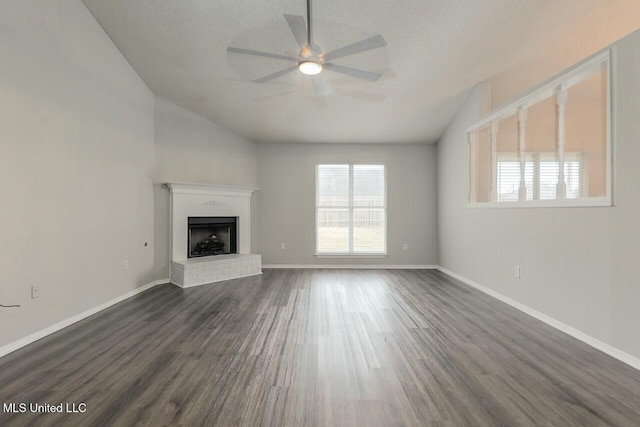 unfurnished living room featuring dark wood-style flooring, a fireplace, lofted ceiling, ceiling fan, and baseboards