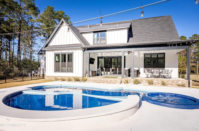 back of house with a swimming pool with hot tub and a patio area