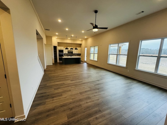 unfurnished living room featuring ceiling fan, vaulted ceiling, crown molding, and dark hardwood / wood-style flooring