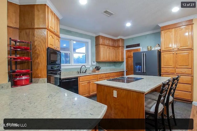 kitchen featuring a kitchen bar, sink, crown molding, a kitchen island, and black appliances