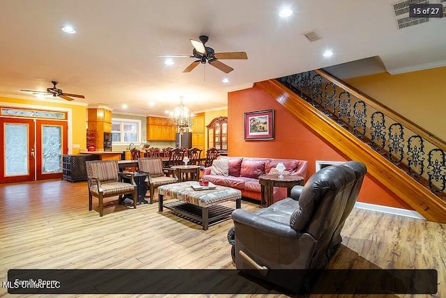living room featuring crown molding, ceiling fan with notable chandelier, and light hardwood / wood-style floors