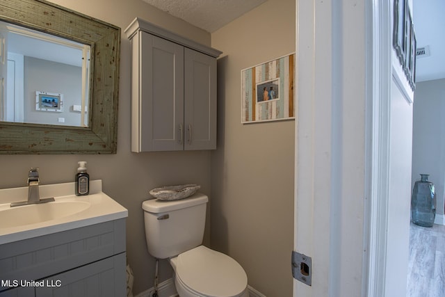 bathroom featuring a textured ceiling, vanity, and toilet