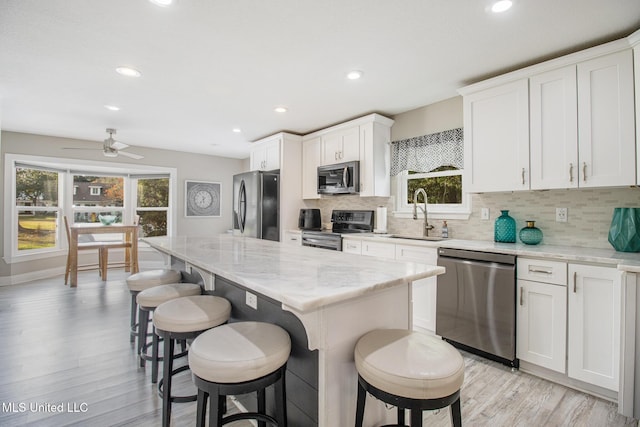 kitchen featuring a center island, sink, light hardwood / wood-style floors, white cabinets, and appliances with stainless steel finishes