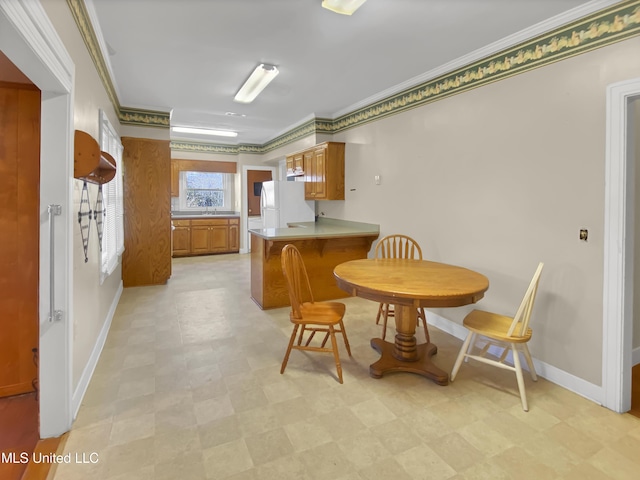 kitchen with white fridge, crown molding, kitchen peninsula, and sink