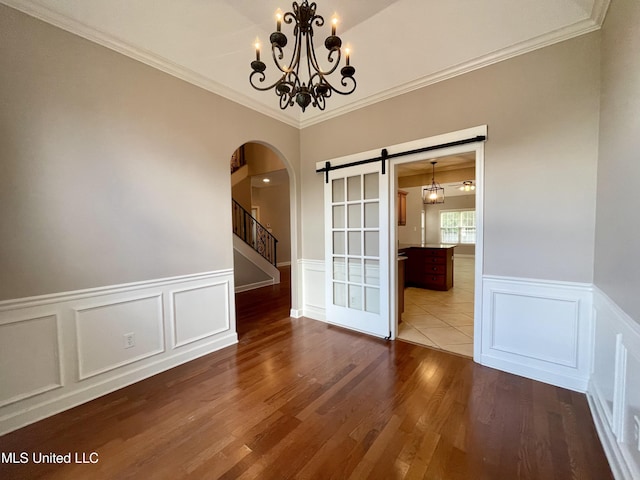 7309 Gerralyn Cv, Olive Branch, MS 38654 - unfurnished dining area featuring arched walkways, wainscoting, a decorative wall, crown molding, and a chandelier