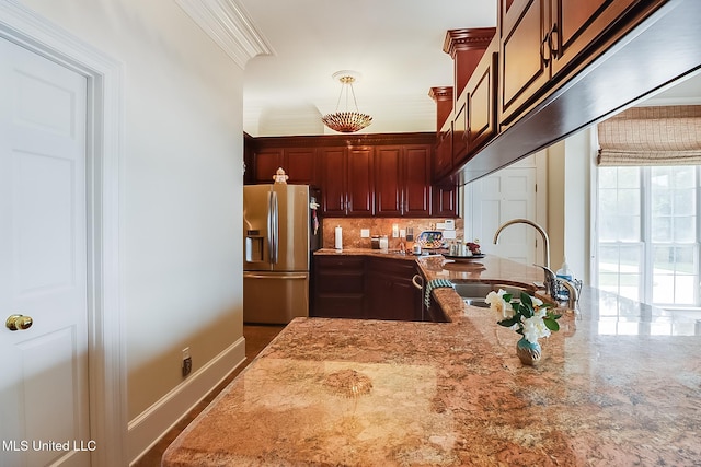 kitchen featuring light stone counters, sink, stainless steel refrigerator with ice dispenser, and tasteful backsplash