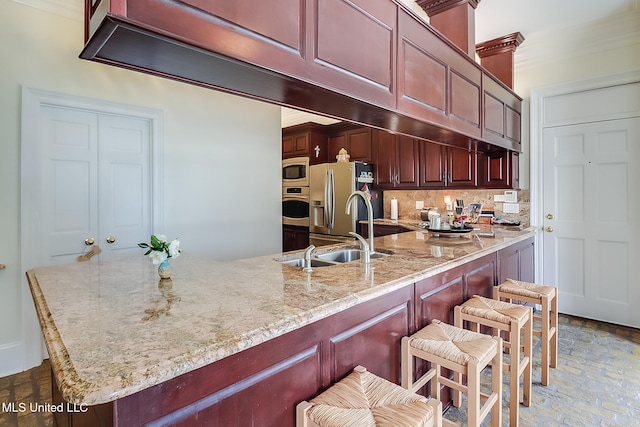 kitchen with a breakfast bar, backsplash, sink, appliances with stainless steel finishes, and kitchen peninsula