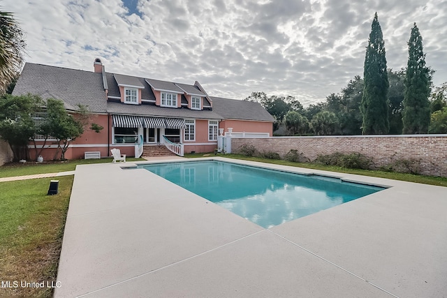 view of pool with a patio and a lawn