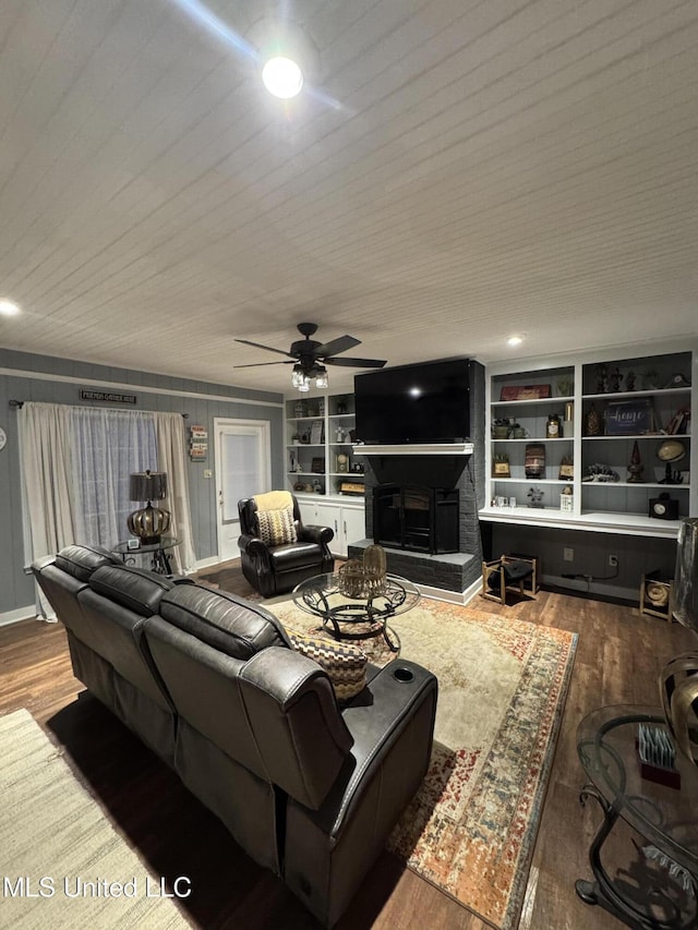 living room with a fireplace, ceiling fan, hardwood / wood-style floors, and built in shelves