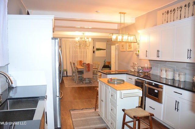 kitchen featuring backsplash, dark wood-type flooring, white cabinets, a kitchen island, and hanging light fixtures