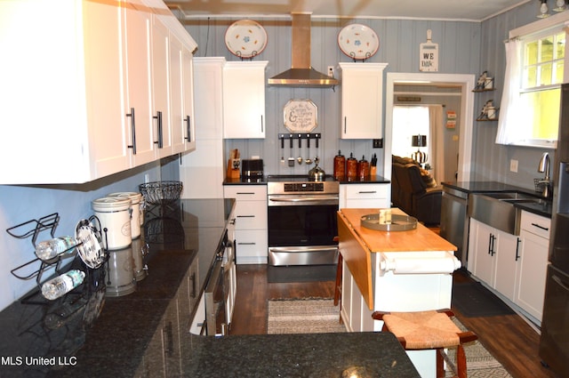 kitchen featuring white cabinets, stainless steel appliances, and wall chimney range hood