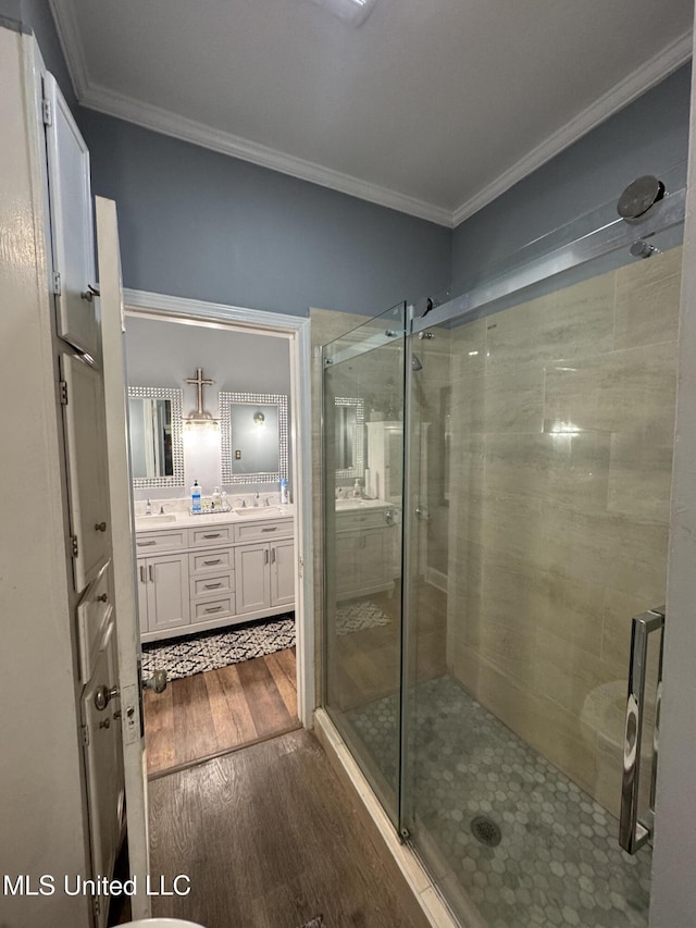 bathroom featuring hardwood / wood-style floors, vanity, a shower with door, and ornamental molding