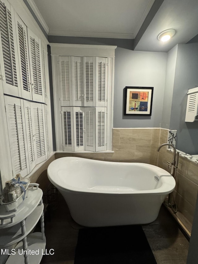 bathroom with a tub, crown molding, and tile walls