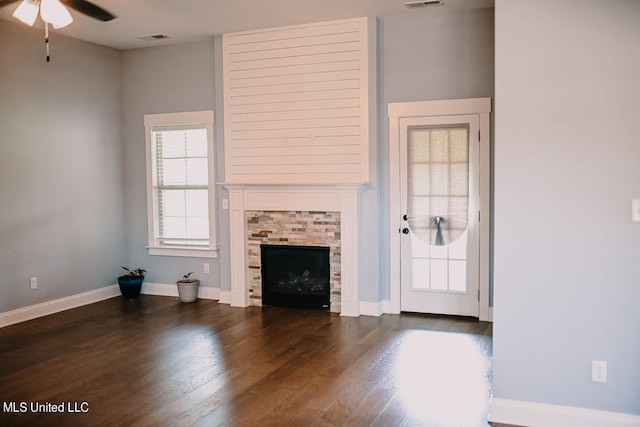 unfurnished living room featuring dark hardwood / wood-style floors, a fireplace, and ceiling fan