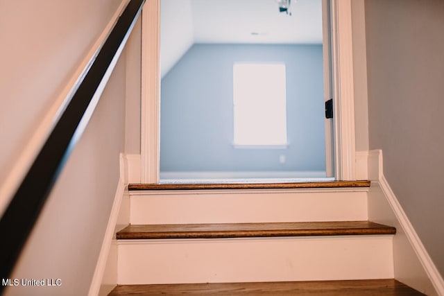 stairs with wood-type flooring and vaulted ceiling