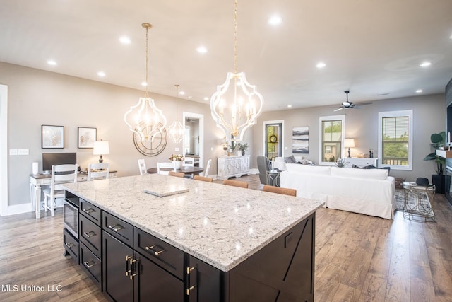 118 Sea Oaks Blvd, Long Beach, MS 39560 - kitchen with a chandelier, ceiling fan, wood finished floors, a kitchen island, and light stone countertops