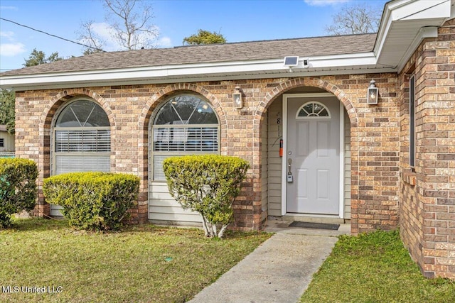 view of exterior entry featuring a lawn