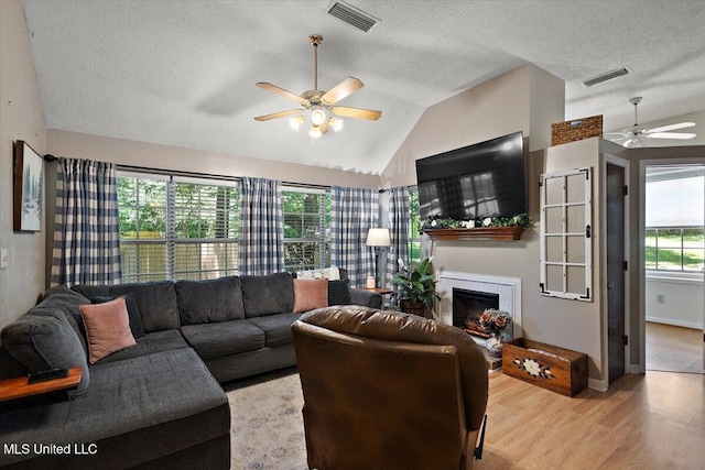 147 Lofty Pine Ln, Clinton, MS 39056 - living area featuring a ceiling fan, lofted ceiling, light wood-type flooring, a tile fireplace, and a textured ceiling