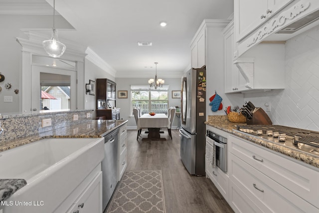 kitchen with visible vents, stainless steel appliances, white cabinets, decorative backsplash, and a chandelier