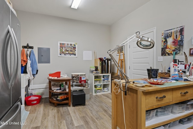 office area with electric panel, baseboards, and light wood-style flooring