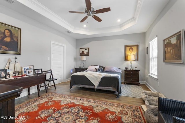 bedroom featuring crown molding, a raised ceiling, and wood finished floors