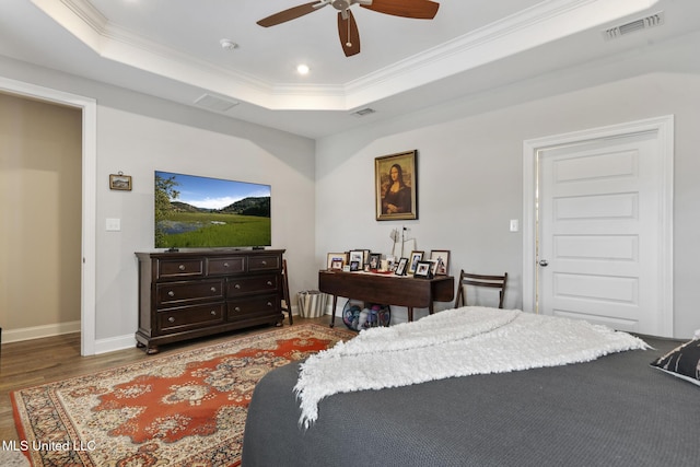 bedroom featuring visible vents, ornamental molding, a raised ceiling, and wood finished floors