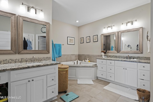 bathroom with tile patterned floors, a bath, two vanities, and a sink