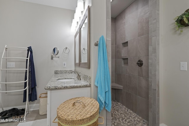 bathroom featuring vanity, baseboards, and tiled shower