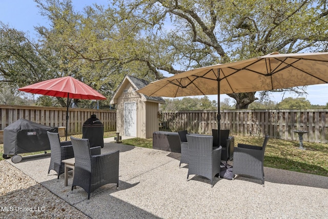 view of patio / terrace with an outbuilding, area for grilling, a fenced backyard, and a shed