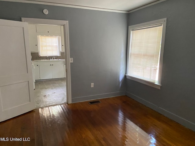 empty room with wood-type flooring and ornamental molding