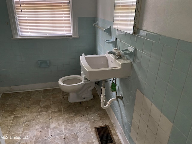 bathroom featuring toilet, tile walls, and sink