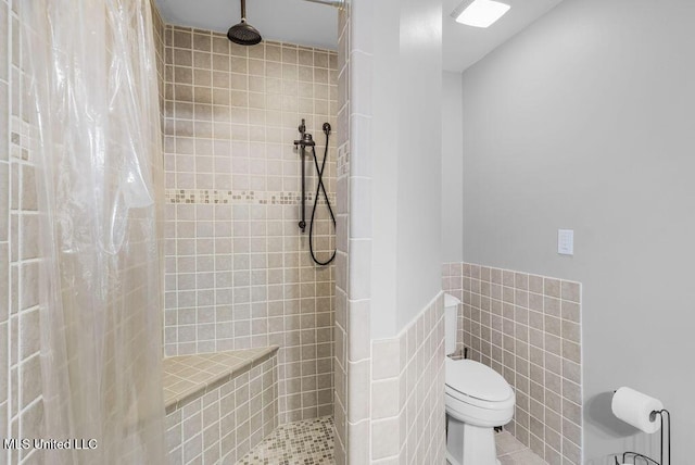 bathroom featuring tile patterned flooring, curtained shower, toilet, and tile walls