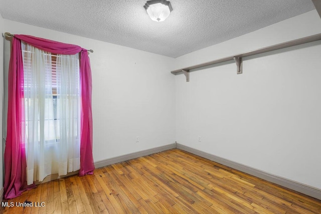 unfurnished room with a textured ceiling and light hardwood / wood-style flooring