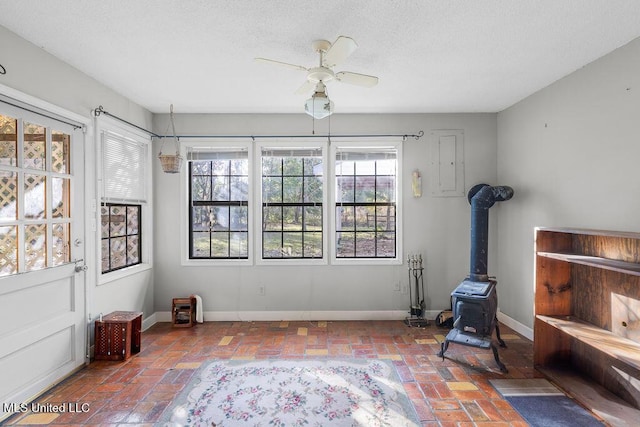 interior space with a wood stove, a wealth of natural light, and ceiling fan