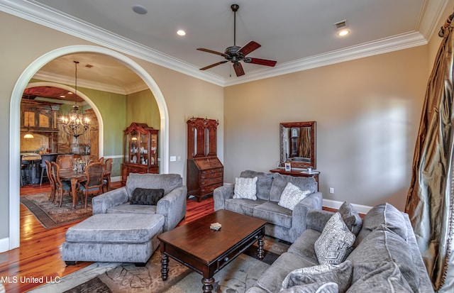 living room with light hardwood / wood-style floors, ornamental molding, and ceiling fan with notable chandelier