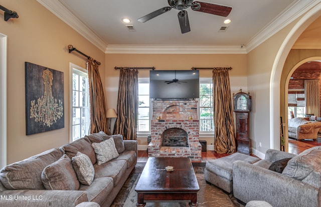 living room featuring crown molding, dark hardwood / wood-style flooring, a fireplace, and ceiling fan