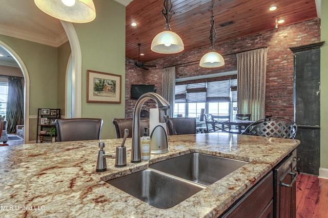 kitchen with hanging light fixtures, wooden ceiling, sink, light stone counters, and dark hardwood / wood-style flooring