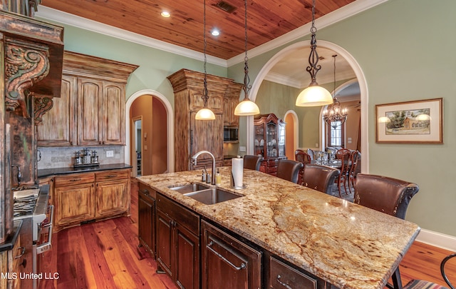 kitchen featuring dark stone countertops, sink, dark wood-type flooring, and an island with sink