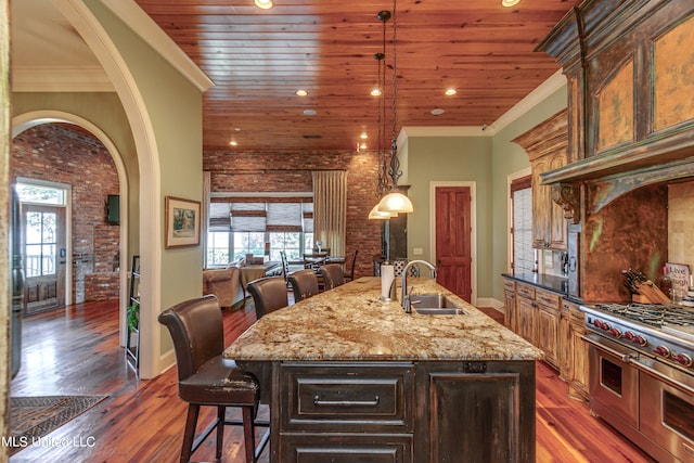 kitchen featuring dark wood-type flooring, a breakfast bar, sink, and an island with sink