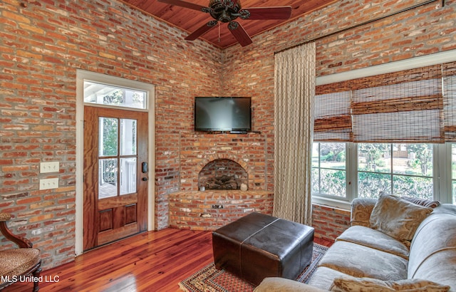 living room featuring brick wall, wood-type flooring, and a wealth of natural light