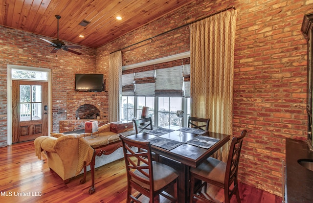 dining area with hardwood / wood-style flooring, brick wall, and ceiling fan