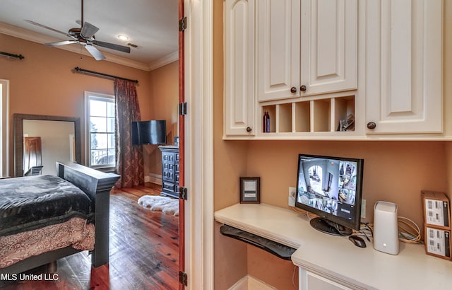 bedroom featuring built in desk, dark wood-type flooring, crown molding, and ceiling fan