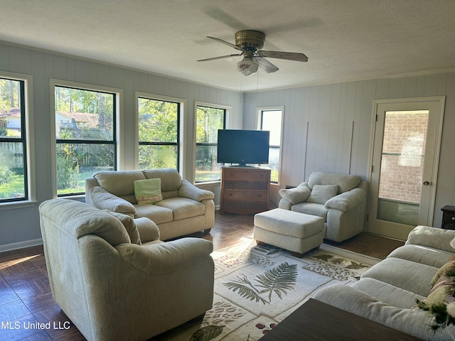 living room with ceiling fan, parquet flooring, and a textured ceiling