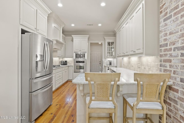 133 Sycamore Rdg, Madison, MS 39110 - kitchen with appliances with stainless steel finishes, a peninsula, white cabinets, light wood-style floors, and crown molding