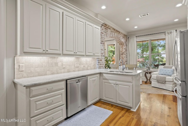 133 Sycamore Rdg, Madison, MS 39110 - kitchen with stainless steel appliances, a sink, white cabinetry, light wood-style flooring, and a peninsula
