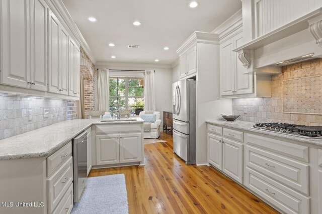 133 Sycamore Rdg, Madison, MS 39110 - kitchen featuring stainless steel appliances, custom exhaust hood, white cabinets, tasteful backsplash, and light wood finished floors